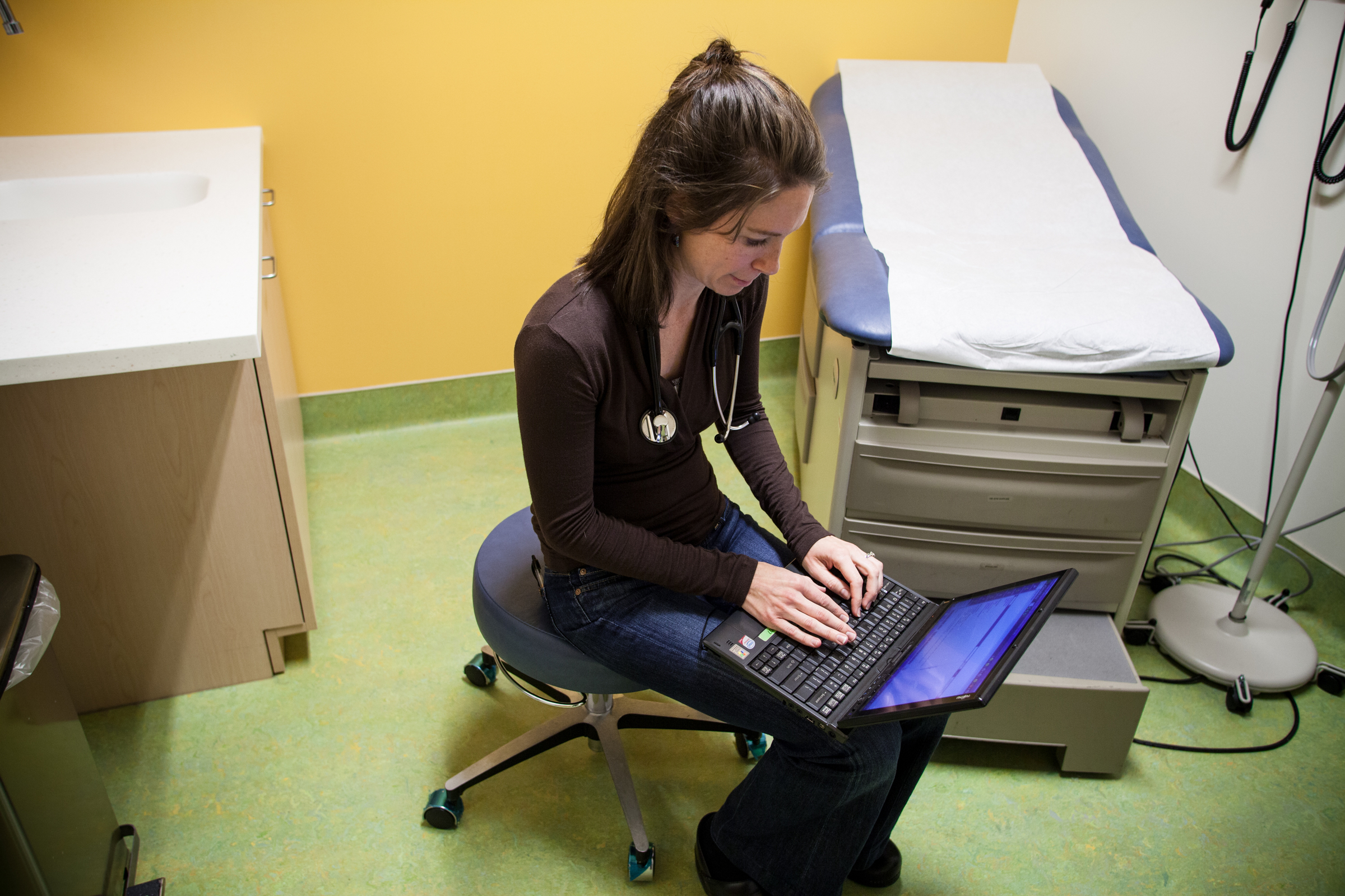 medical professional types on a laptop