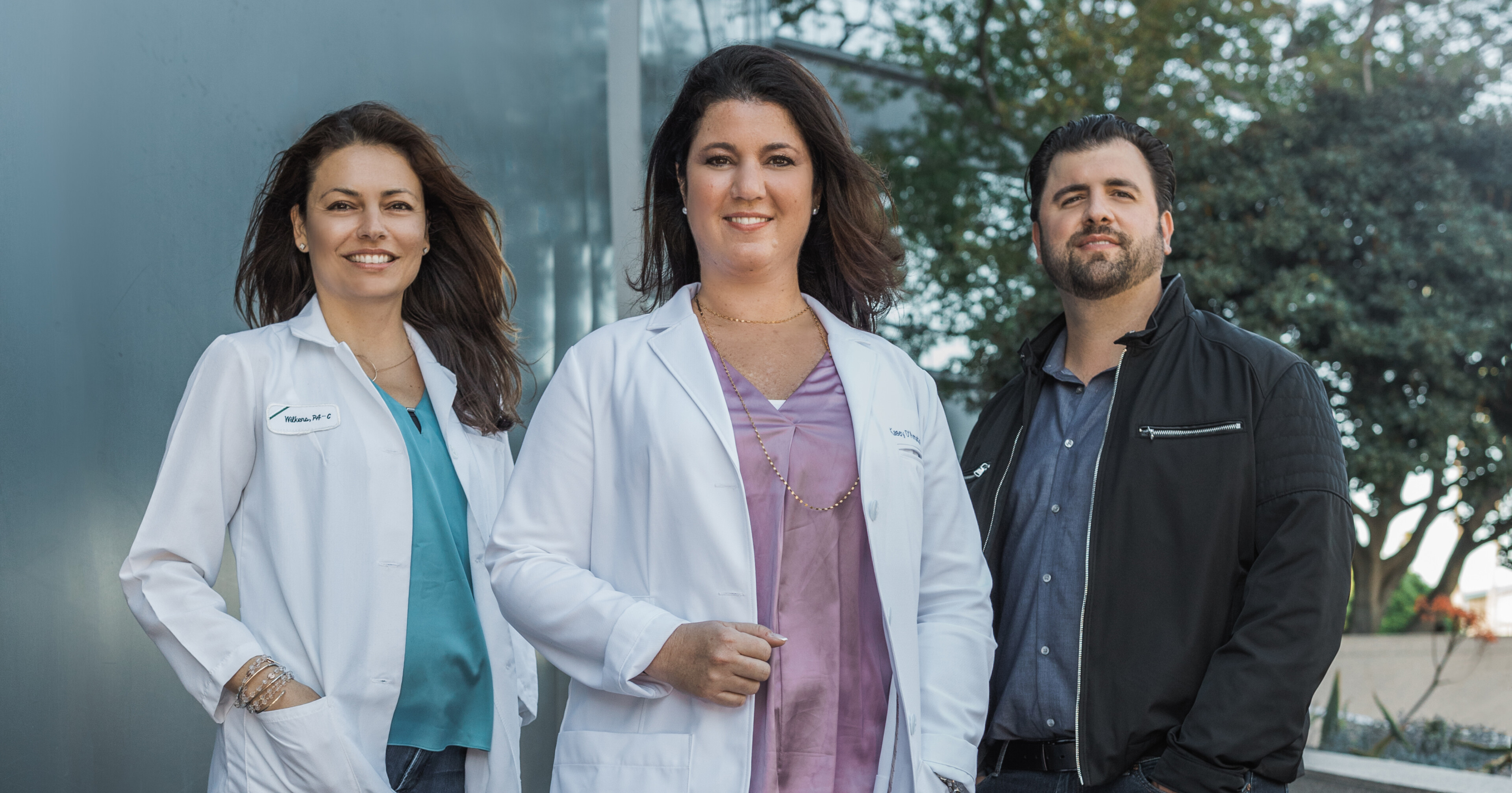 Katherine Wilkens, Kasey Drapeau D’Amato, and Stephen D’Amato posing outside