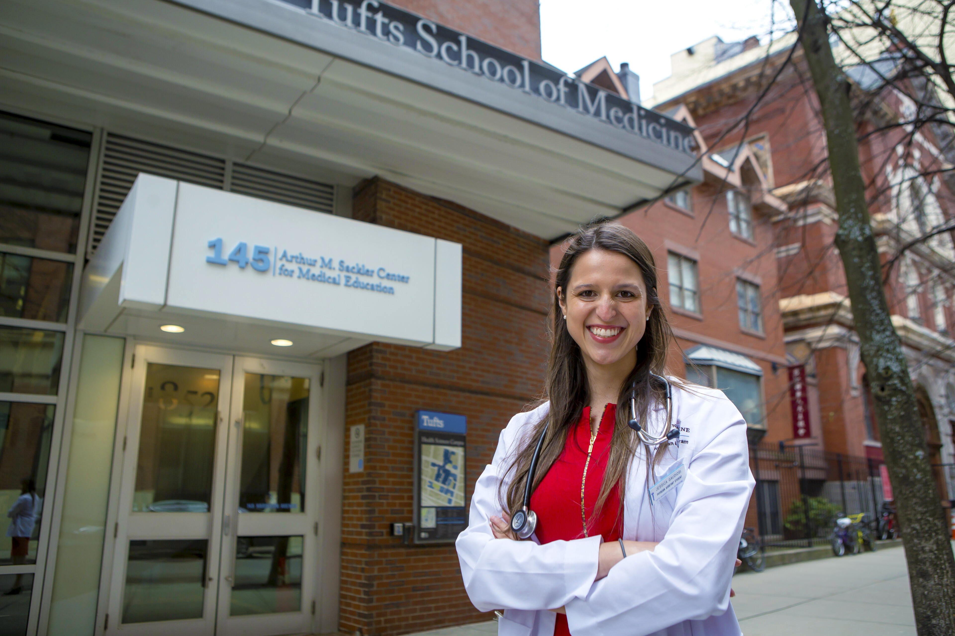 Jessica Gaudiosi smiling with arms crossed in front of the Tufts School of Medicine