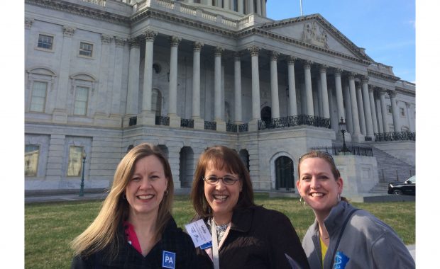 Three women pose in front of the Capitol building