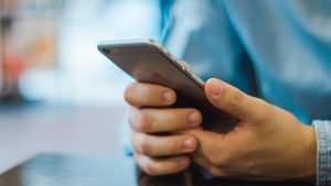 Man in blue shirt holding an iPhone