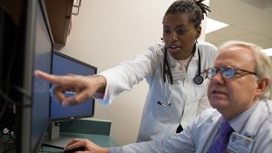 Two physician associates/physician assistants looking at the computer