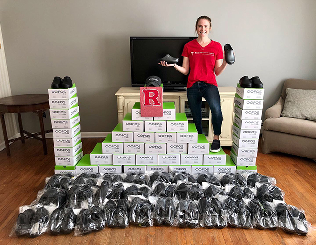 Molly deButts standing next to many pairs of shoes