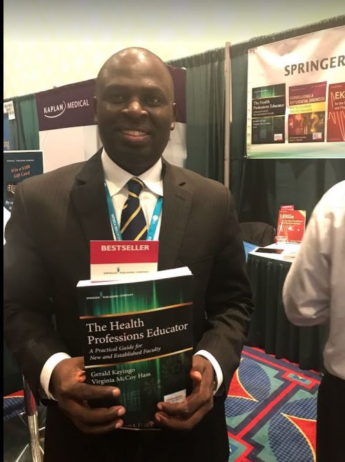 A man holds a book he authored titled, "The Health Professions Educator."