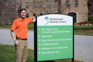 Man stands next to a building sign